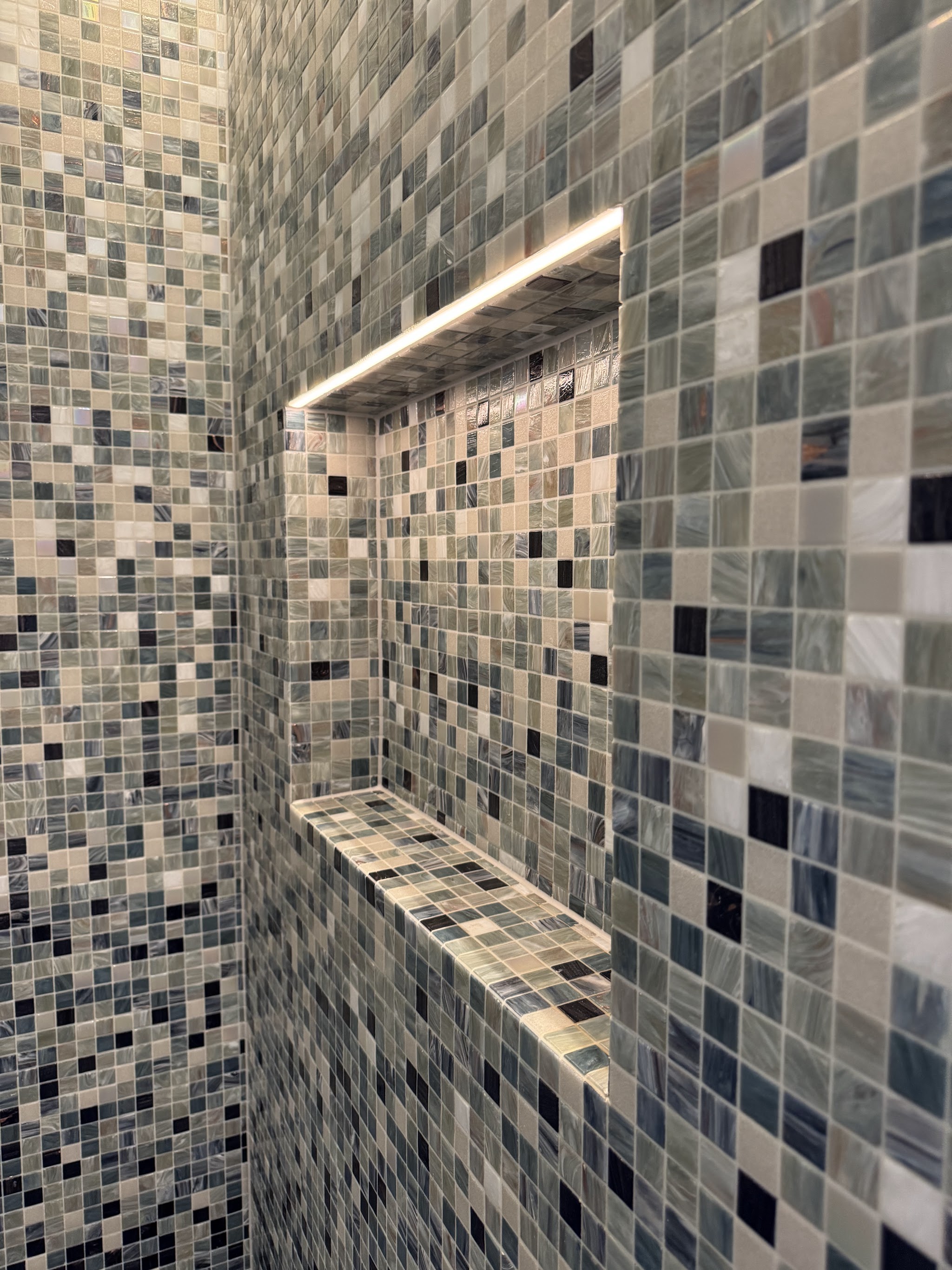Dusche mit blau-grauem Mosaik und beleuchteter Nische