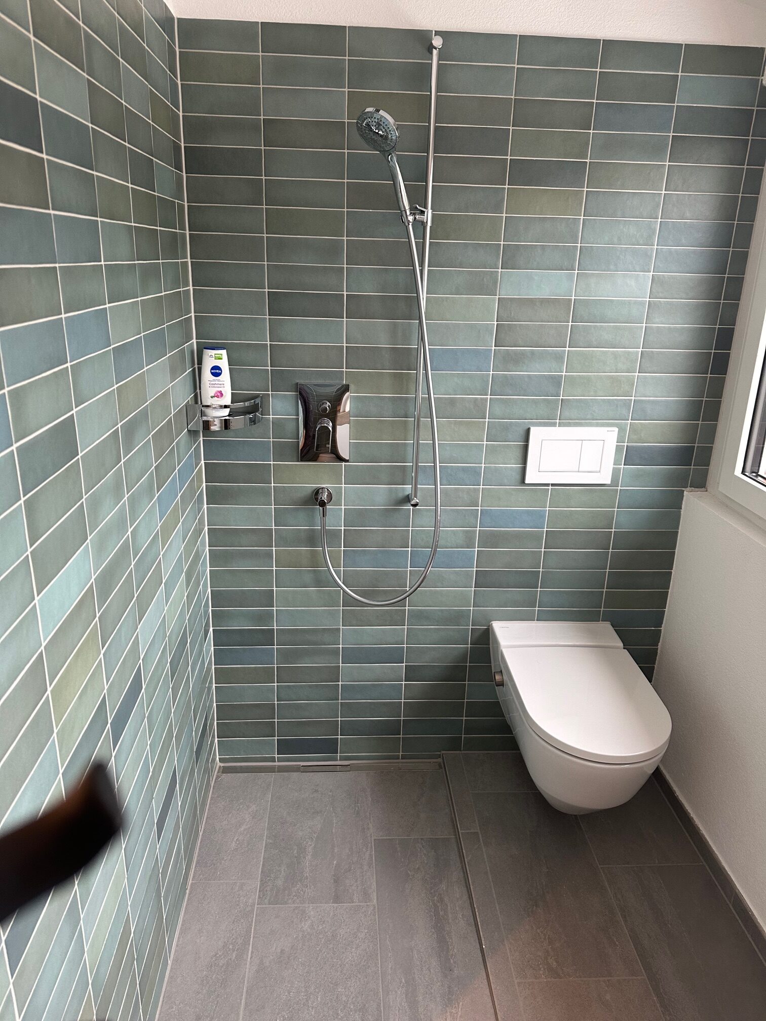 Dusche mit grün-grauen, hochkant verlegten Platten