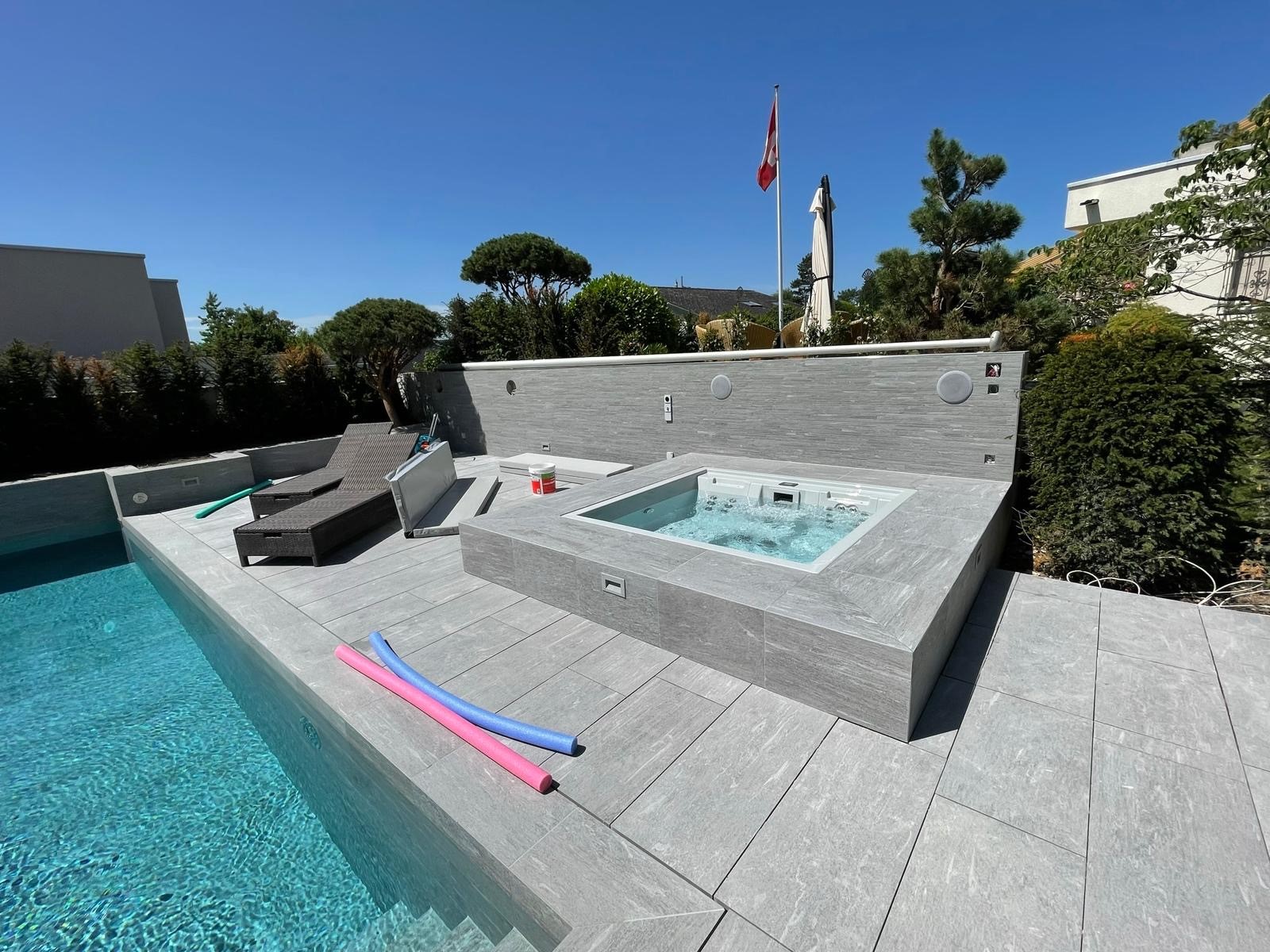 Terrasse mit Steinplatten rund um Pool und Whirlpool